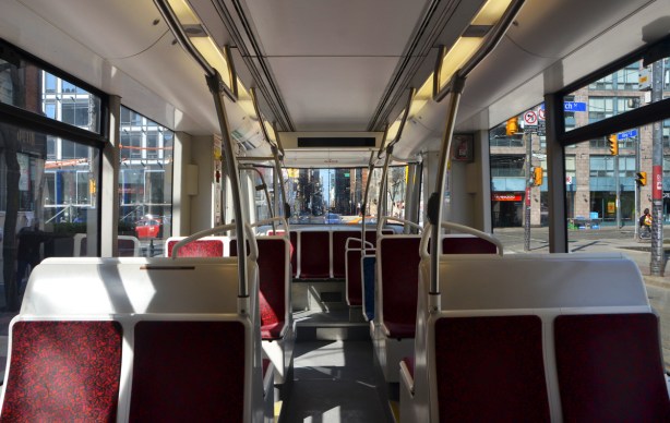 interior of a TTC streetcar, looking towards the back, red covered white seats, no one else on the car. 