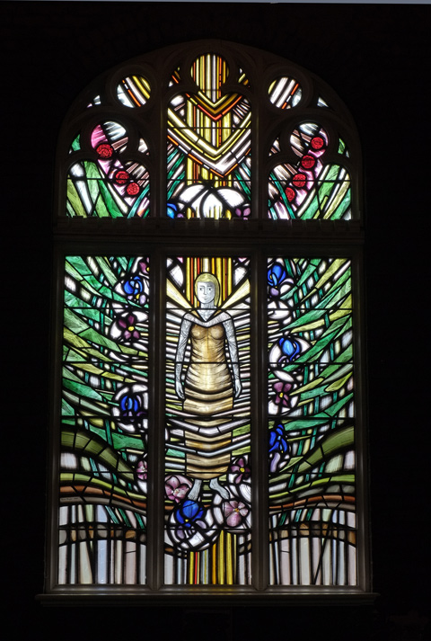 stained glass window by Stephen Taylor, memorial to the women of St. Simons, with a woman in the center, roots wrapped around her and greenery growing out from her, 