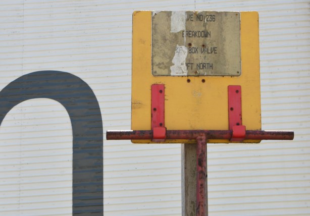 yellow wign held up by red metal brackets. faded sign, 