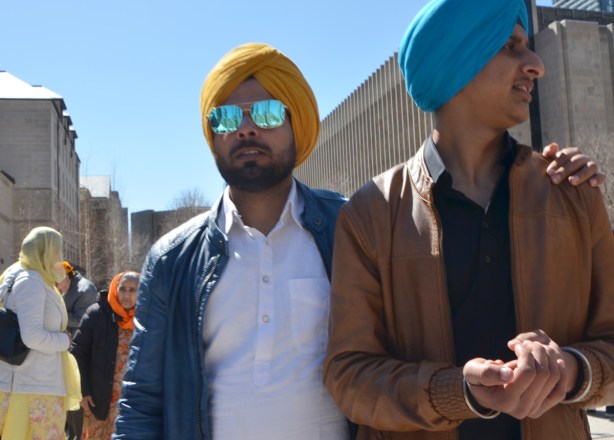 two young men in turbans, one blue and one yellow. one is wearing reflective sunglasses 
