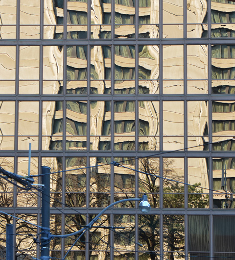wavy reflections of a building in the windows of another downtown building