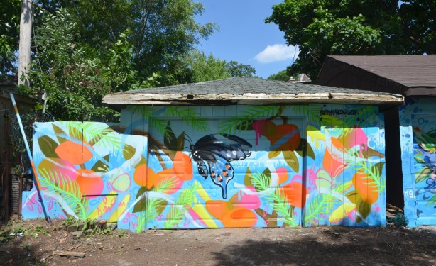 mural running horizontally across garage, garage door and adjoining fence, butterflies and flowers