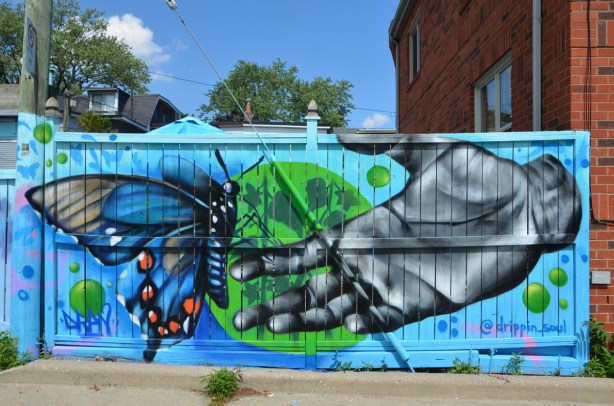 a mural by @drippin_soul of a hand reaching towards a blue butterfly