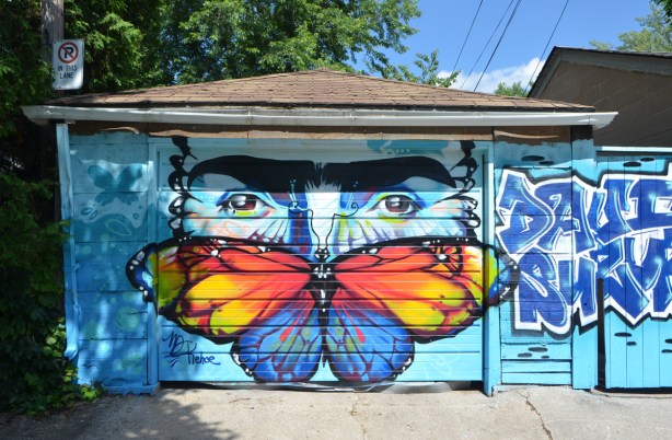 a butterfly and a face merged into one, the eyes look out over the top of the red and yellow wings 
