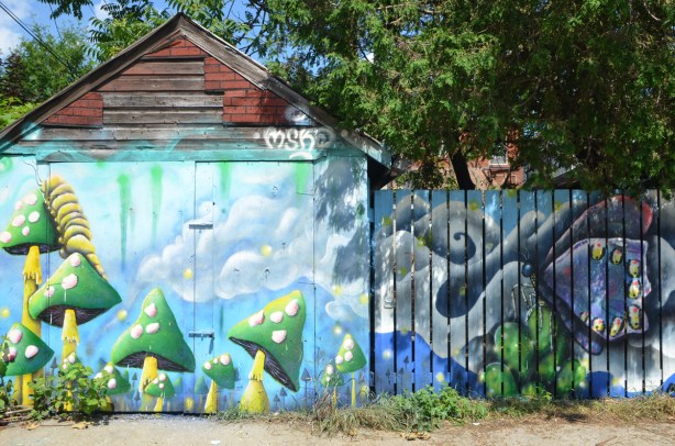 mural by mska on a garage door and fence, green and yellow toadstools