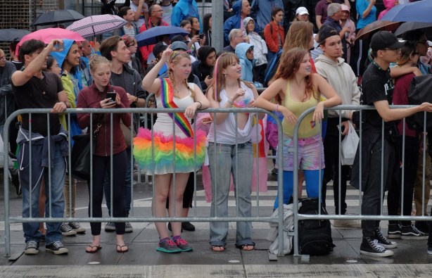 behind metal barricades, people watching the pride parade 