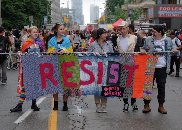 dyke march 2018 - a group of people carrying a banner made of yarn, crocheted, that says resist. #dmto #resist 
