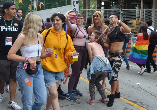 a group poses for a selfie shot as other people walk by 