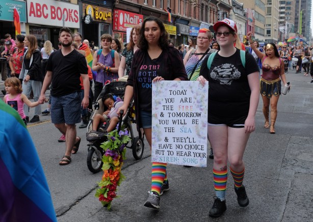 groups of people walking in dyke march 2018, two are holding a sign that says today you are the fire and tomorrow you will be the sea and they'll have no choice but to hear your siren song a sign that says 