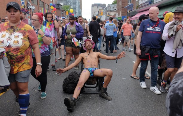 crowds on church street, with a man in just underwear sprawled on a chair in the middle of the street 