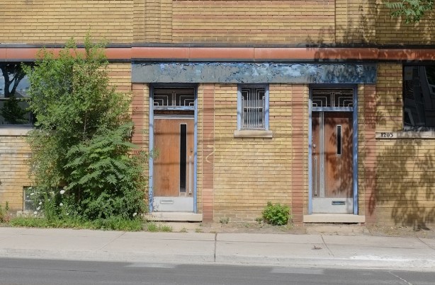 two doors side by side with art deco motifs, on a low rise brick building