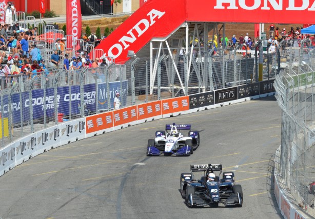 two race cars pass by stands at Honda Indy 