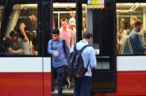 people in the midst of getting on and off a streetcar