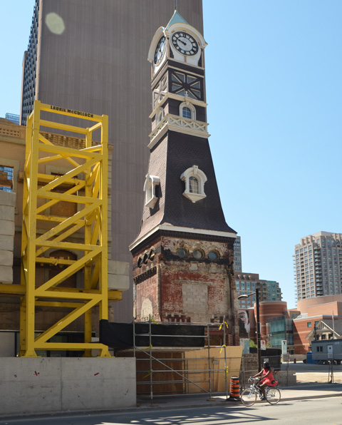St. Charles tavern clock tower stands on a construction site as a woman on a bike cycles past 