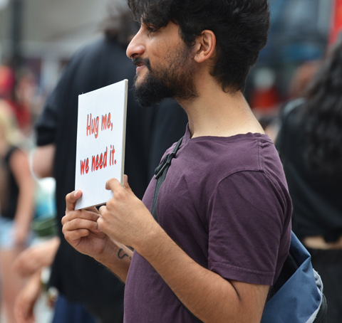 a young man holds a sign that says hug me we need it 