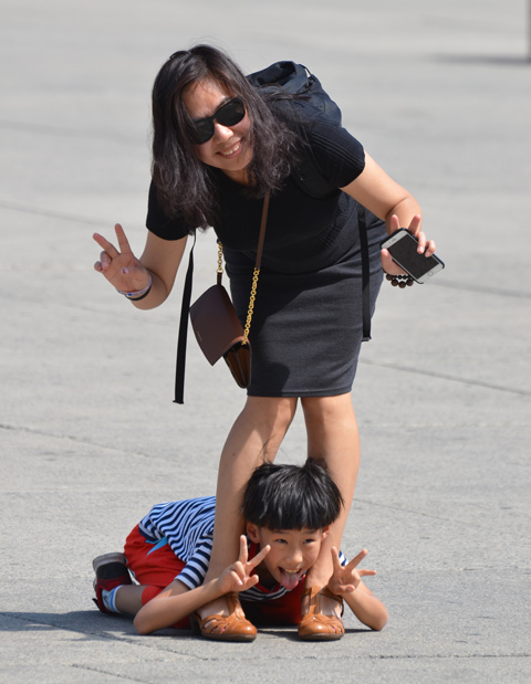 mother and son posing for picture, Asian, boy is lying on the ground between his mother's feet