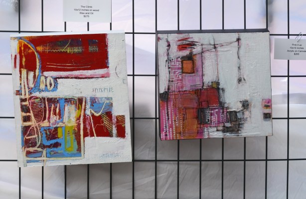 two small paintings on wood, hanging on a metal grid