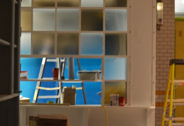 looking in the window of a construction site, two ladders, square panes of interior glass on a wall 