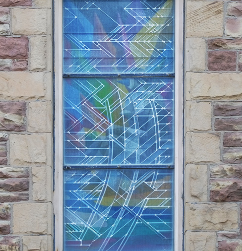 part of mural, equilibrium by okudart, reflected in church windows across the street from it 