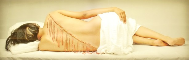 fringe, by Rebecca Belmore, a photo of a woman's back as she's lying down, scar and beads