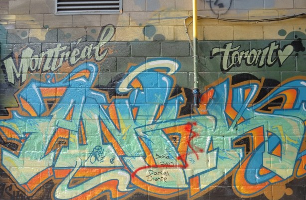 text street art with the words Montreal and Toronto written in the top corners 