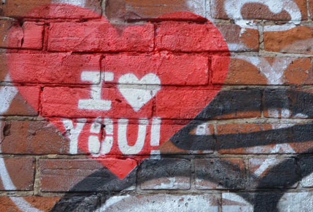 graffiti on a brick wall, red heart with words I love you, instead of the word love there is a white heart