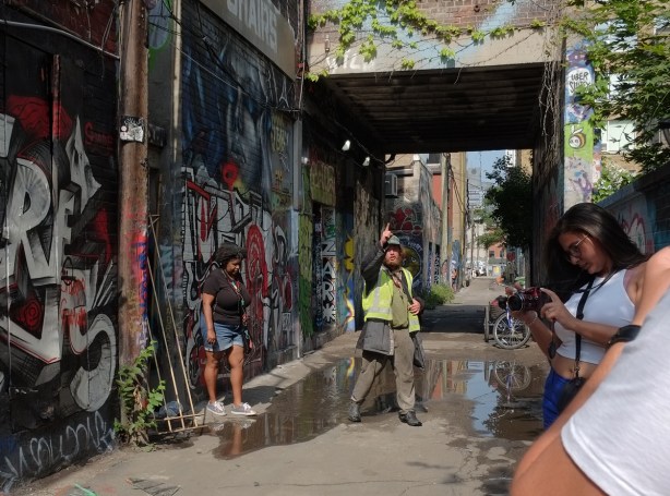 a man in a yellow vest is talking in Graffiti Alley 