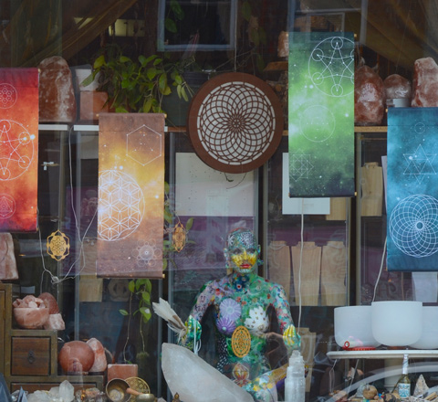 window of a store in Kensington market area, mannequin sitting cross legged that has been painted 