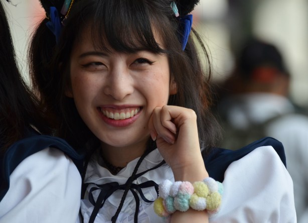 asian woman in navy and white frilly anime french maid costumes, with hair tied up with bows, pompom bracelet on