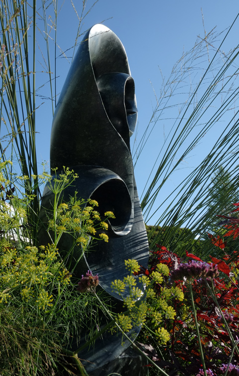 tall stone sculpture among plants in a garden 