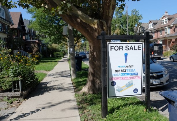 for sale sign on the grass in front of a house