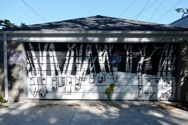 garage door covered with a mural of a boy walking in a birch forest in the snow with his dog following him