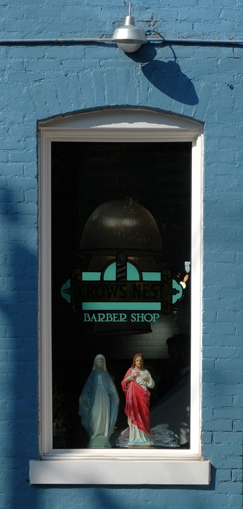 the window of Crows Nest Barber with a statue of Mary and a statue of Jesus in the window 