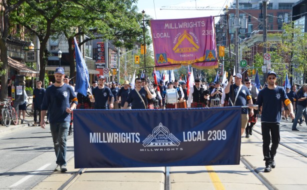 millwrights local 2309 walk with their banner in a labour day parade 
