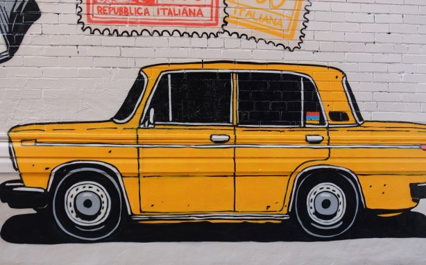 part of a mural in a narrow alley in Kensington by Dave Setrakian, a parrot on a perch and an airplane, a large yellow car