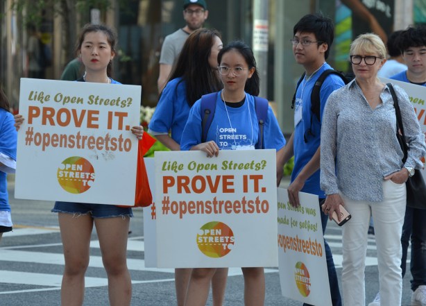 two young women holding signs that say, Love Open Streets, prove it. #openstreetsto