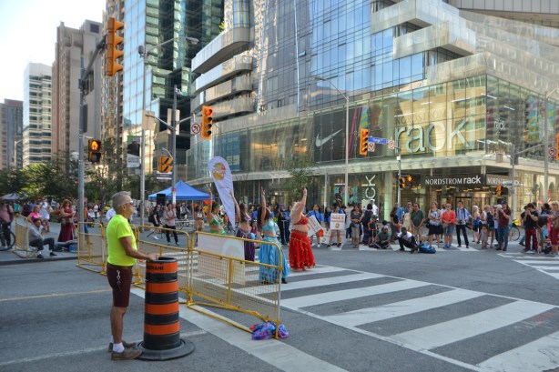 the intersection of Yonge and Bloor at Open Streets, belly dancers performing for an audience, Nordstroms Rack store in the background