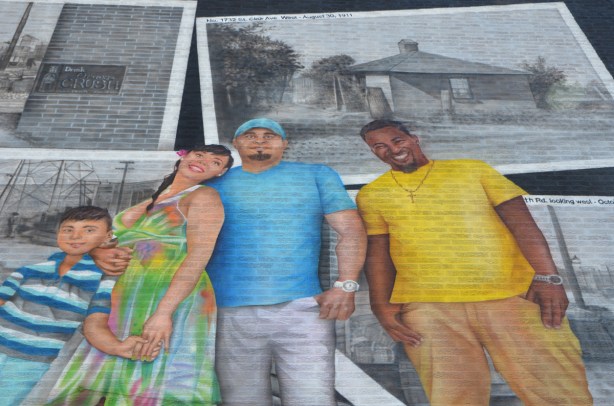 painting, in colour, of a group of people standing in front of paintings of some old monochrome historical pictures of the St. Clair area