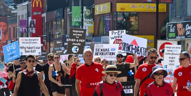people wearing red T-shirts and carrying signs, walking in a walk to raise funds and awareness for AIDS, on Yonge Street.