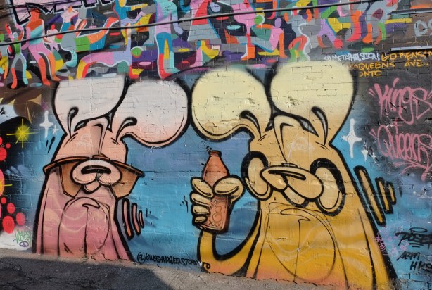 poser bunny mural on a brick wall, a pinkish bunny and a yellow one, the yellow bunny is holding a bottle of alcohol
