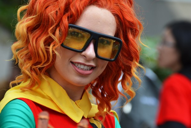 a woman dressed as Robin, Boy Wonder, reddish orange wig, and large glasses