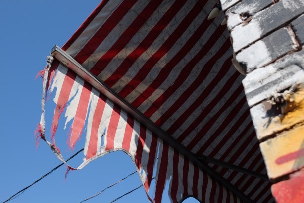 red and white striped awning above a store, tattered 