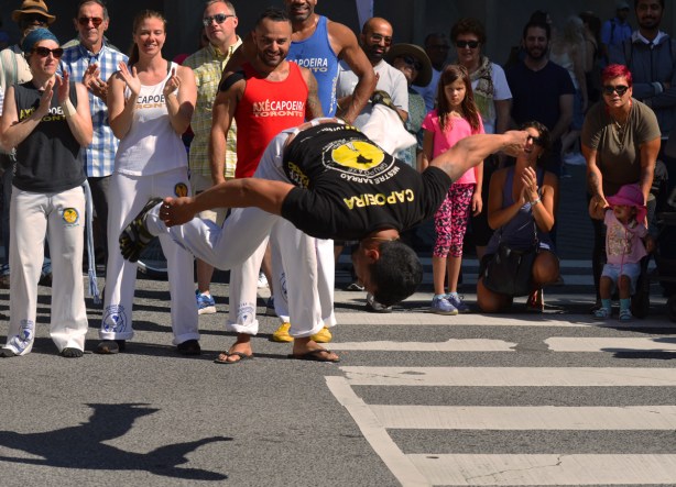 a man is flipping upside down in front of an audience on the sidewalk