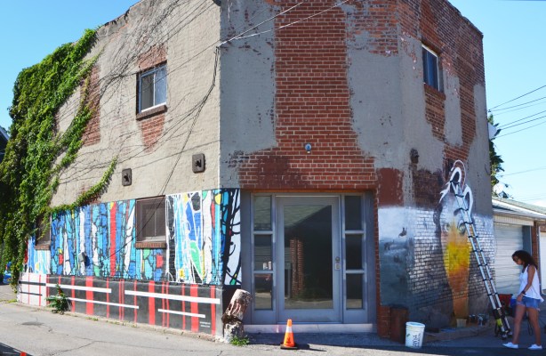 old building in an alley with murals being painted on two sides