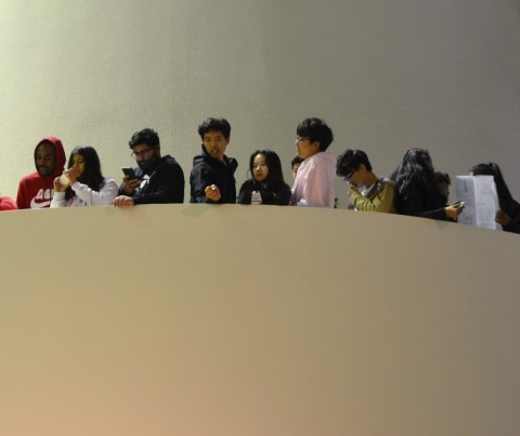 people line the edge of a balcony to watch a performance below