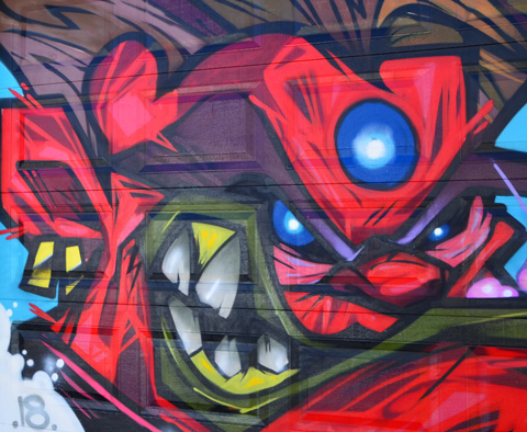 close up of ugly red face in mural by cruz 1, big blue eye and green mouth with large crooked teeth
