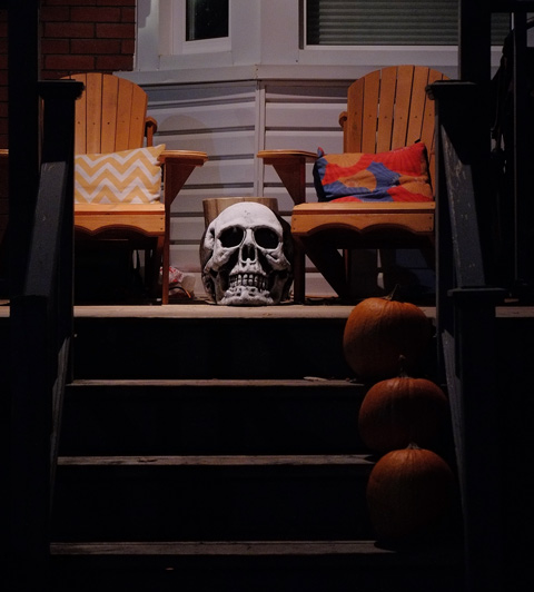 a skull sits on the porch at the top of the stairs. 