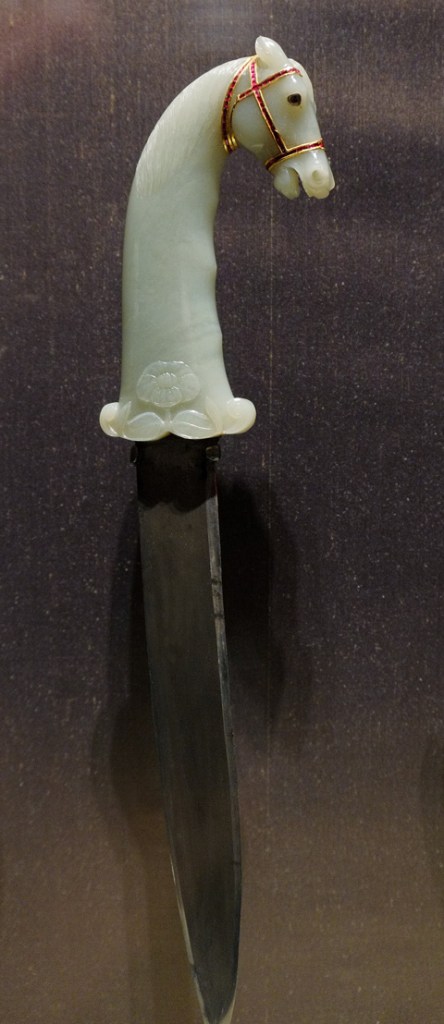 on display at the Aga Khan Museum, a metal knife iwth a jade handle that is carved into the shape of a horse head and neack, decorated with gold bridle 