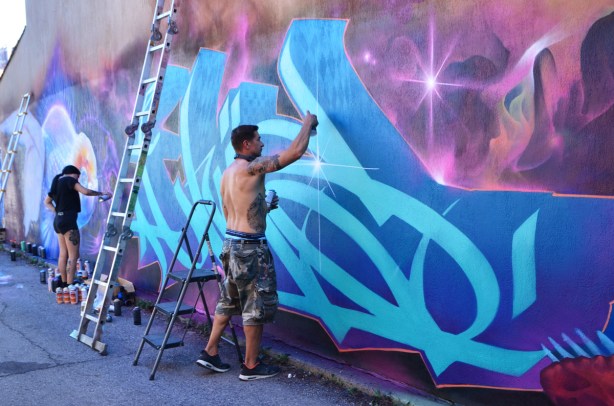 Nick Sweetman painting a mural in a laneway, alley mural