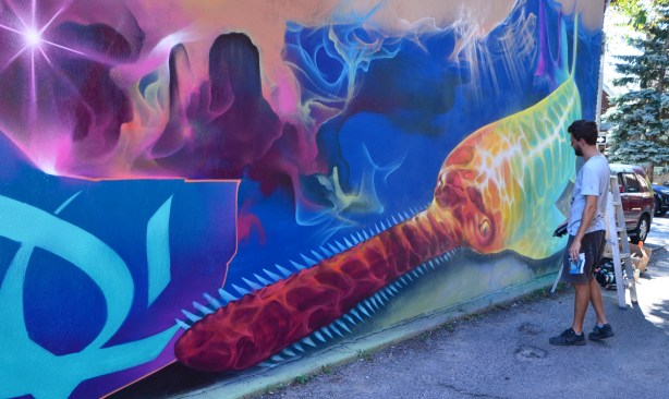 Nick Sweetman works on a mural of a narwhal